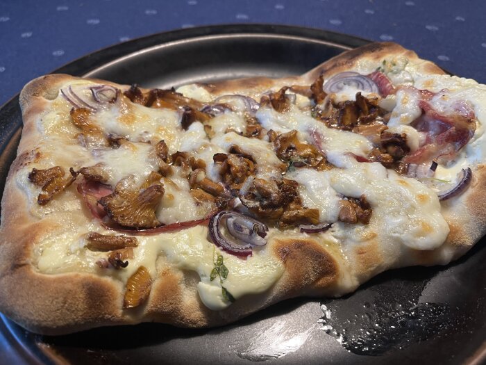 Pizza med kantareller, lök och ost på en krispig botten.