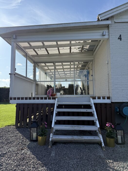 Skjutpartier installerade på en utbyggnad med trappa, omgiven av blommor och ljuslyktor. Klart väder ger en ljus och öppen känsla.