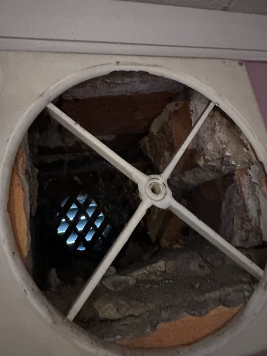 Friskluftsventil i tegelvägg utan rör, med synliga tegelstenar och galler.