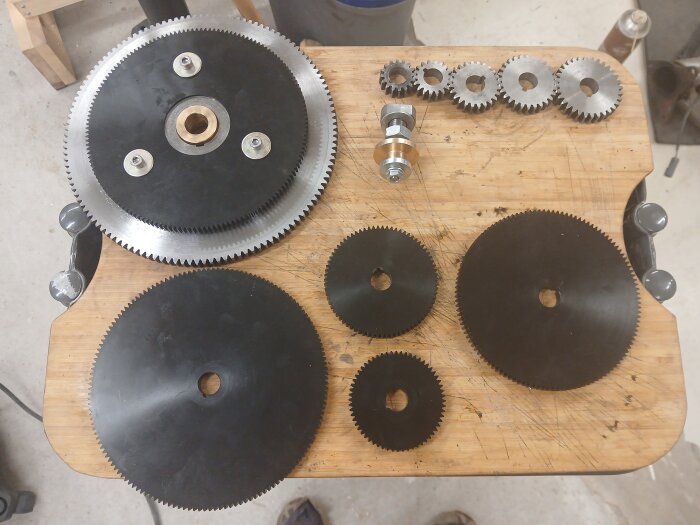 Drev och axeldelar för svarvprojekt, inklusive mellanhjul och bussning, placerade på en träyta.