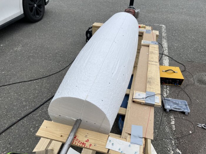 Hemmagjord maskin för skärning av cellplastcylinder med hjälp av en het tråd, uppsatt på lastpallar.