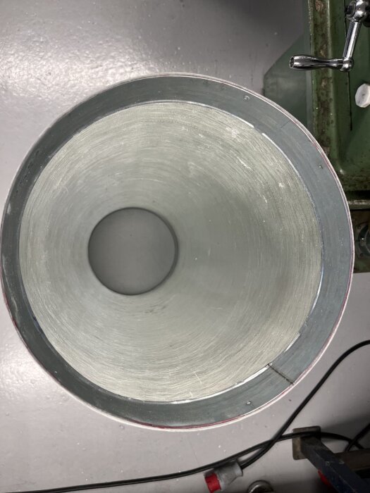 Öppningen av en ihålig cylinder med en rund metallkant, del av ett byggprojekt för att skapa en batteribox.