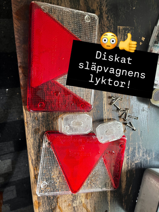 Röda och vita släpvagnslyktor ligger på ett träbord, tillsammans med skruvar. Texten "Diskat släpvagnens lyktor!" syns över bilden.