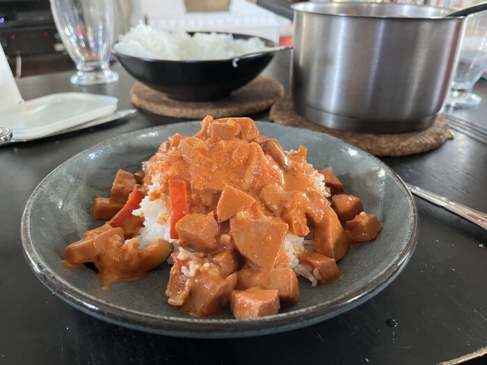 Tallrik med korvgryta av falukorv, lök, champinjoner, squash, krossade tomater och paprika, serverad med ris.
