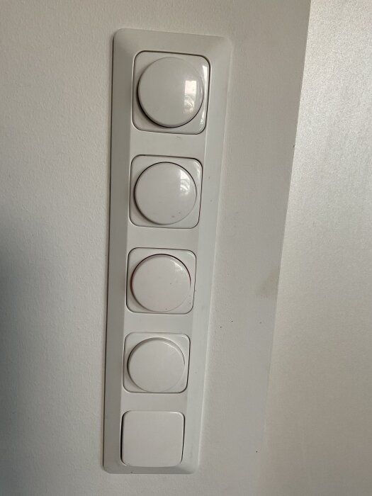 Panel med fem vita vred monterade på en vägg.