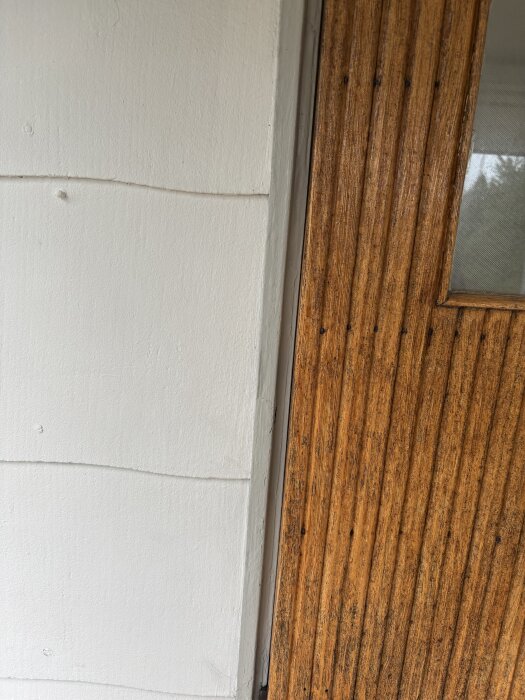 Dörr med träram och vit eternitfasad i sommarstuga, frågor om plåt för dörrkarmsinstallation.