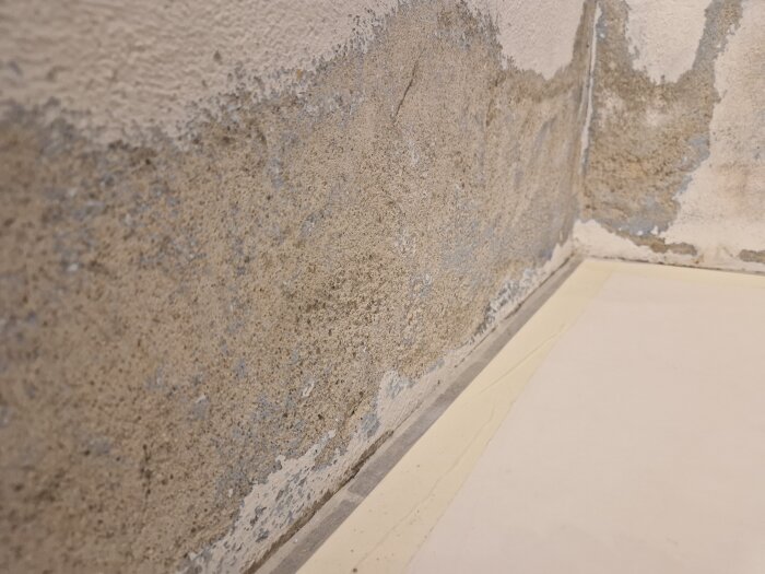 Närbild av en vägg med avflagnad färg, synliga texturer och vita beläggningar, som visar resultatet av slipning och rengöring med stålborste.