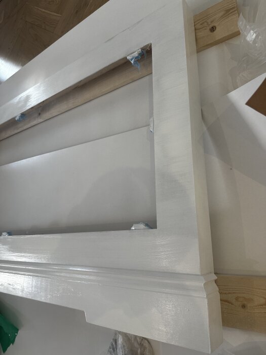 Målat elementskydd under konstruktion, prima och slipat yta, redo för slutstrykning. Vågräta och lodräta penseldrag syns på dess träytor.