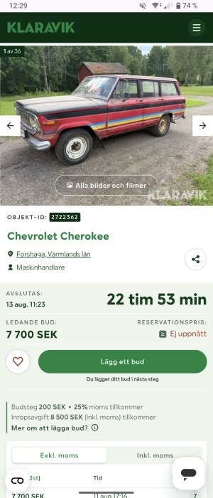 En röd och svart Chevrolet Cherokee med färgade ränder, parkerad utomhus framför en röd byggnad och grönska.