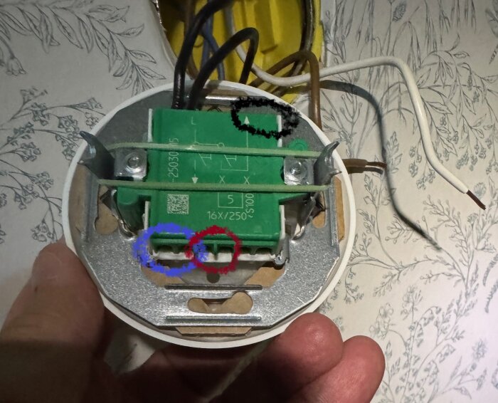 Närbild av elströmställarens baksida med markerade pilar i svart, blått och rött och flera anslutna elsladdar.