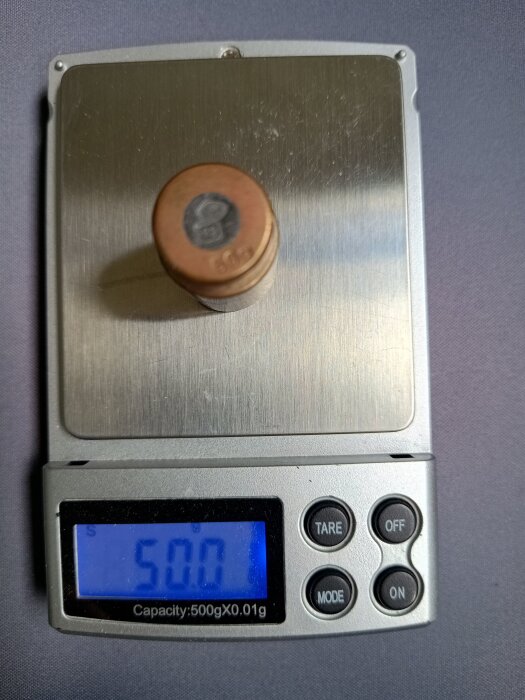 Digital köksvåg visar 50,0 gram med ett viktskott på plattformen. Mellan precision anges till 0,01 gram.