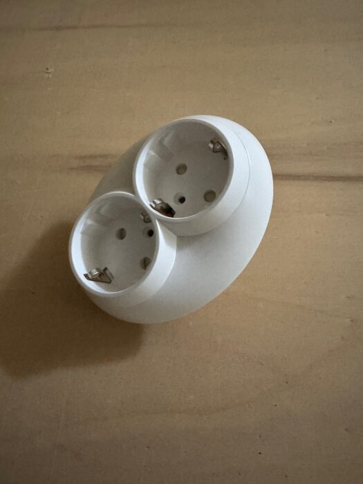 Dubbelgångigt eluttag Schneider Renova placerat på en kartongliknande yta, visas uppifrån.