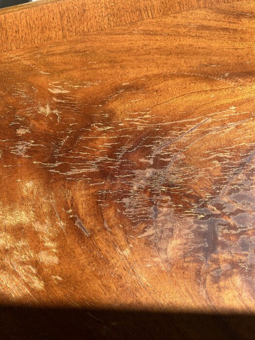 Krackelerad bordsyta med hård, spröd lack och några små skador i faneret, möjligen orsakade av shellack på gammalt bord köpt på loppis.