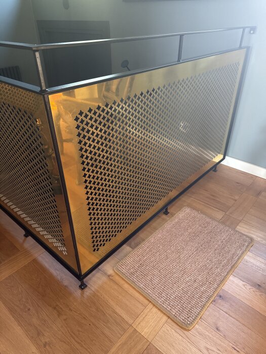 Mässingsplåt med stjärnmönster monterad på pulverlackat stål i ett trappräcke, med ett matta på golvet.