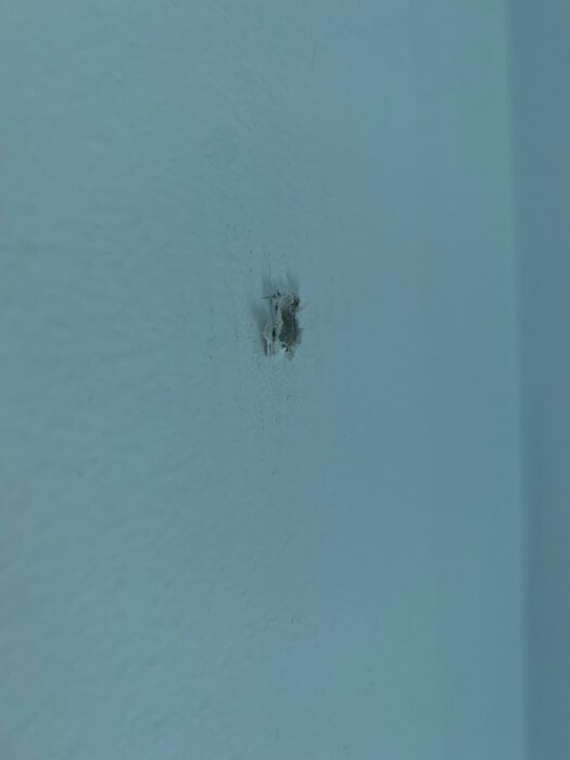 Hål i en blå vägg, troligtvis orsakat av en lyft, behöver jämnas ut innan spackling.