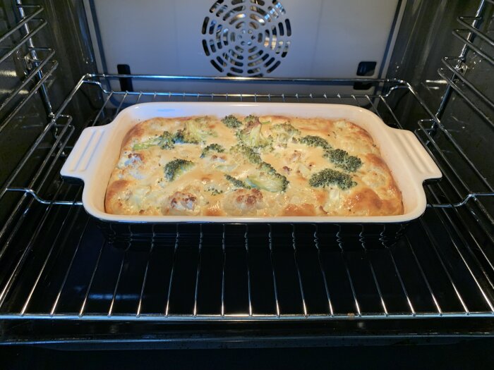Broccoli och blomkålsgratäng bakas i en ugnsform med gyllenbrun yta, placerad i en ugn.