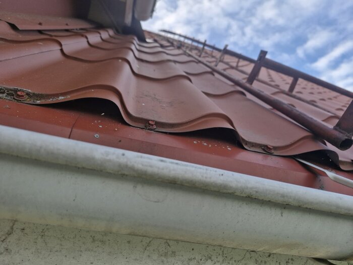 En bild på ett rött tak med korrugerad plåt och en vit hängränna.