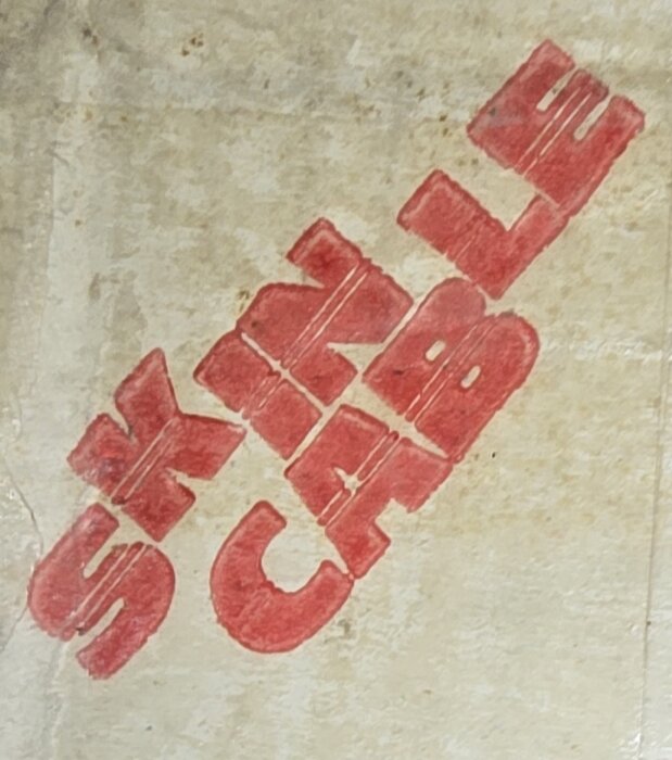 Röd text stämplad på en ljus bakgrund, texten är svår att tyda men kan vara relaterad till ledningar eller italiensk produktbeskrivning.