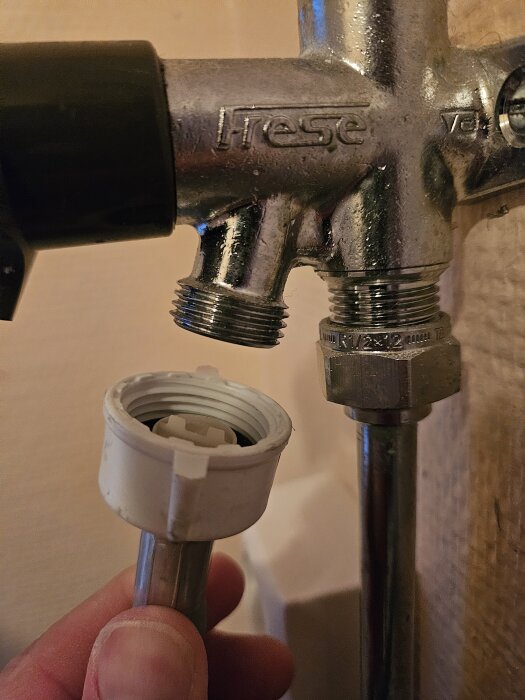 Anslutning av en tvättmaskinsslang till en vattenkran med olika gängstorlekar, 3/4" och 1/2", i en gammal stuga.