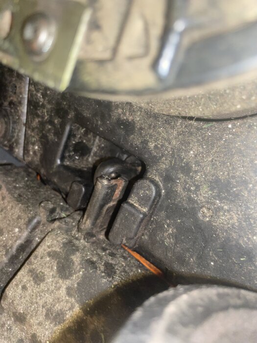 Närbild av insidan på en maskin där en del av en krocksensor visar sig, omgiven av smuts och metallkomponenter.