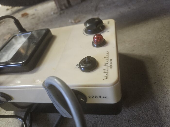 Närbild av en elektrisk enhet med vridknappar och en röd indikatorlampa, märkt "220V AC" och med texten "Wilh. Nielsen Denmark.