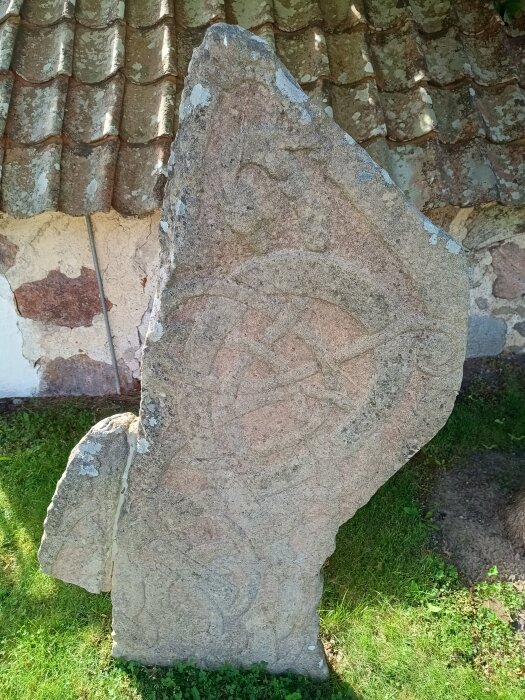 Runsten ristad av Balle vid Husby Rekarne kyrka, delvis sliten och fragmenterad med slingermönster, rest på nuvarande plats 1860.