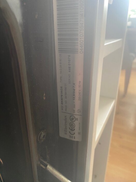 Etikett med serienummer och modellinformation på en Electrolux spis, inklusive CE-märkning och produktkod.