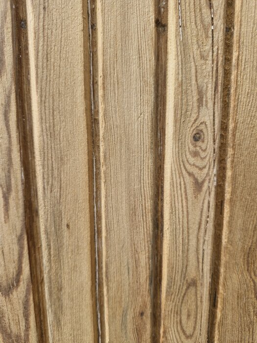 Träpanel med tydliga ådringar och knutar, möjligtvis från en garageport från 1953.