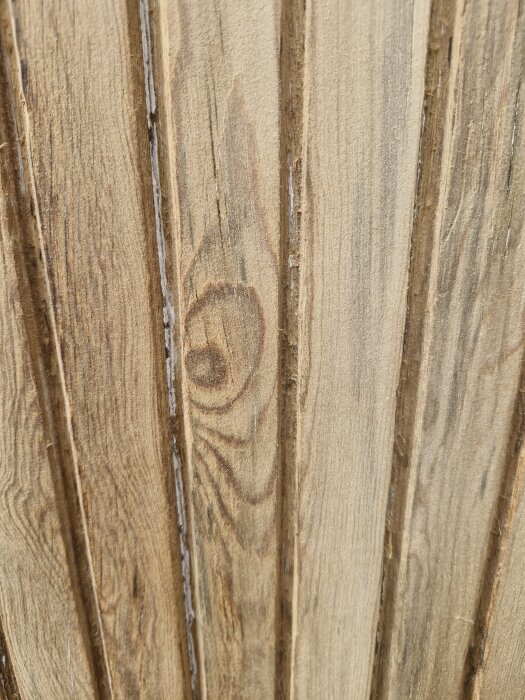 Närbild på en träyta med tydliga ådringar och spår av bearbetning, potentiellt från en garageport från 1953.