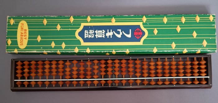 Japansk kulram i trä med tillhörande grön kartong märkt "Best Fuk'i Abacus".