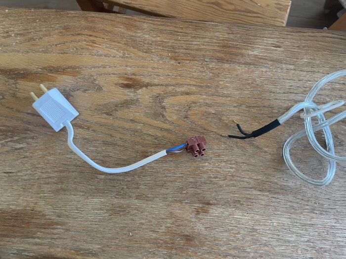 Ojordad vit lamppropp kopplad till en brun sockerbit på en träyta, ansluten till genomskinlig kabel med guldig ände.