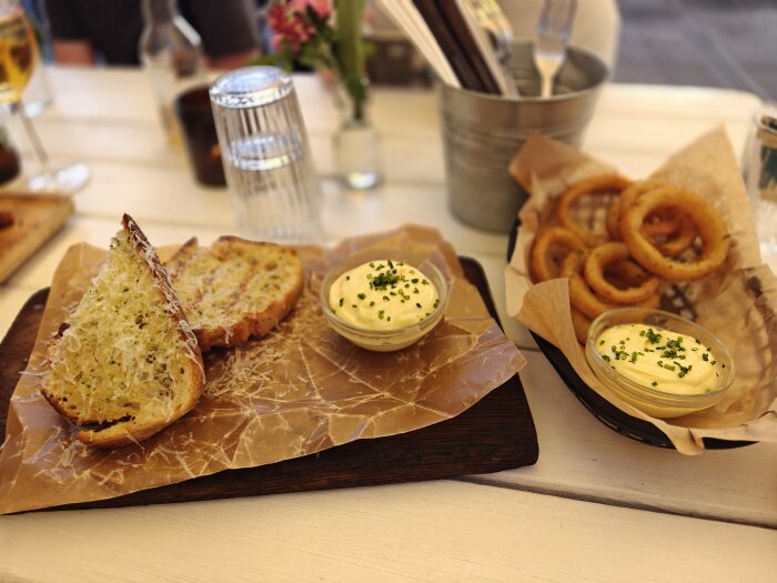 Vitlöksbröd med riven ost och friterade lökringar serveras med dipp, på ett matbord under bbq i Borgholm.