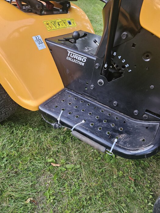 Fjäder är tillfälligt fastsatt med buntband på en orange maskin, markerad "Turbo Collection", stående på gräs.