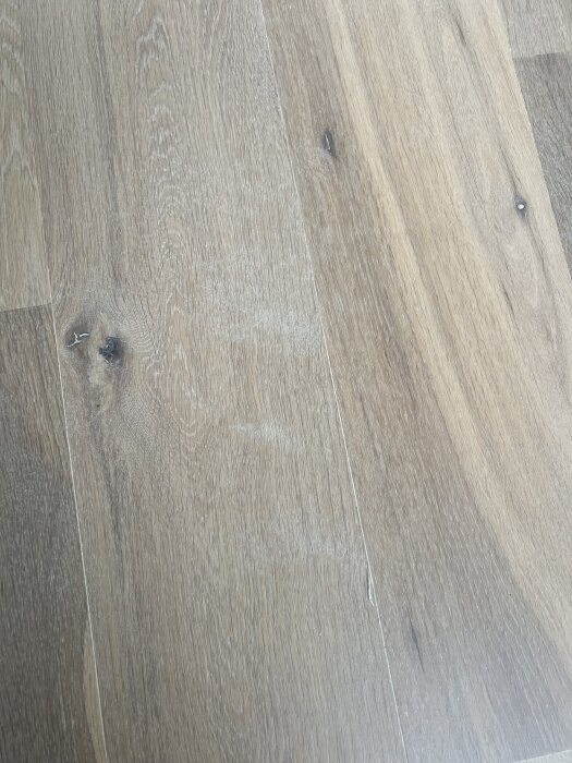Ekparkett med slipmärken och vita fläckar.