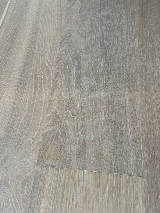 Slipat ekgolv med flammigt utseende och små repor synliga i träets struktur.