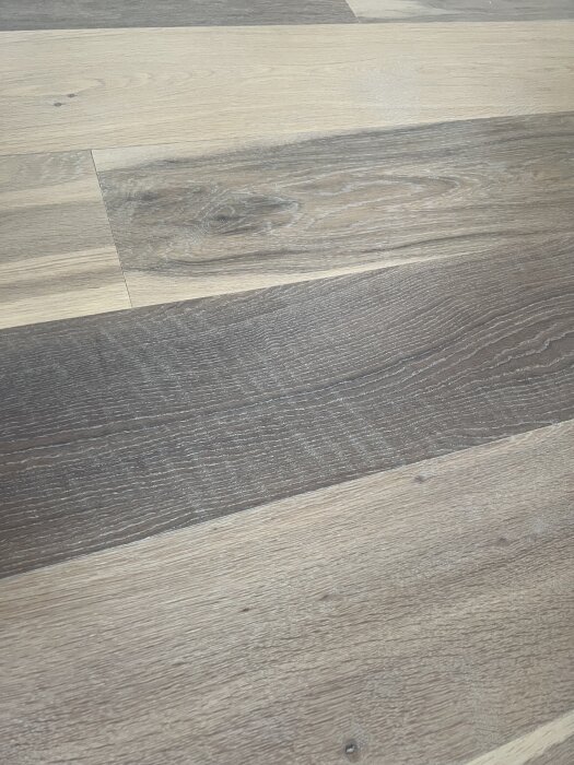 Slipade ekgolvbrädor med synliga repor och flammiga ytor, visar resultatet av en golvslipning och orsakar missnöje hos ägaren.