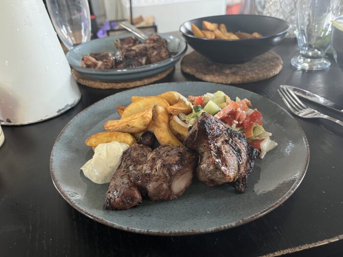 Tallrik med grillade revben, klyftpotatis, grönsallad och bearnaisesås.