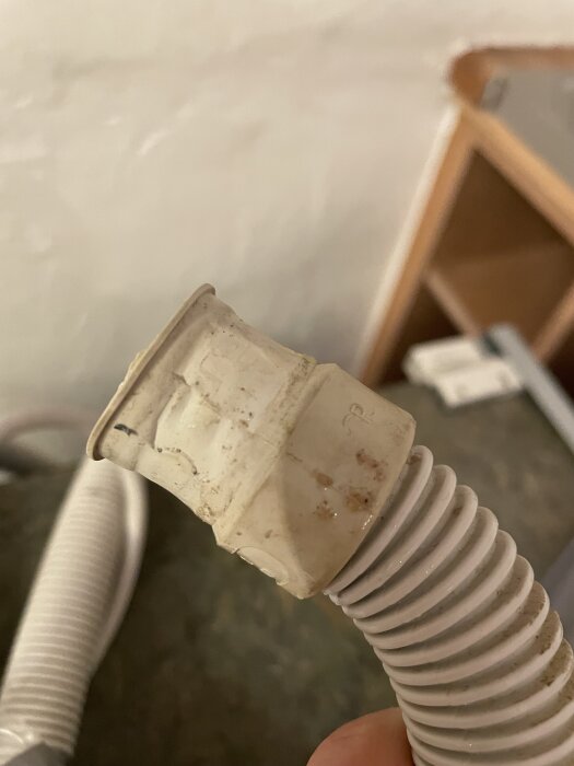 Avloppsslang med en klämma syns i närbild mot en suddig bakgrund, sannolikt ett hemprojekt.