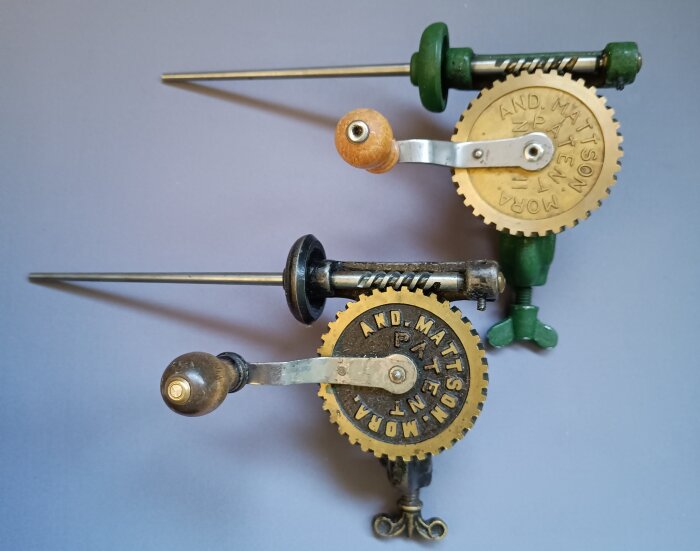 Två tråduppspolningsapparater av gammalt och nytt utförande, med kugghjul och vev, på en lila bakgrund.