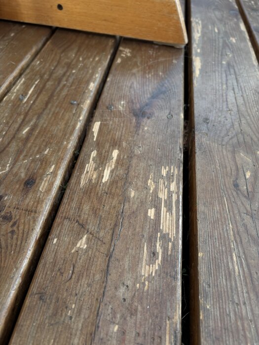 Slitet altangolv med flagor avsaknad av färg och synliga träfibrer.