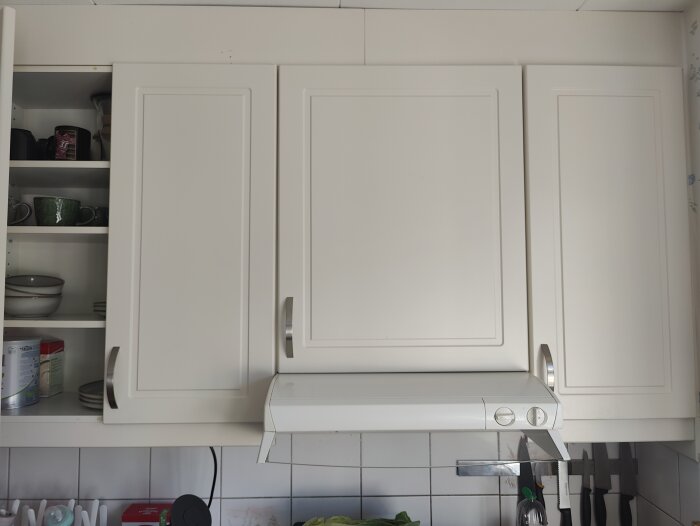 Köksöverskåp med vit köksfläkt under. Undersöks för möjligheten att ta bort ett skåp utan att påverka stabiliteten.