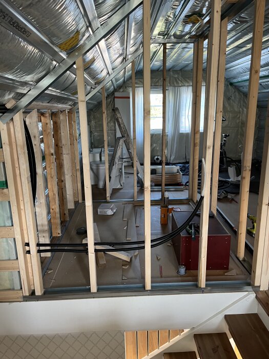 Byggarbetsplats för badrum med träreglar och verktyg. Lite byggmaterial ligger på golvet.