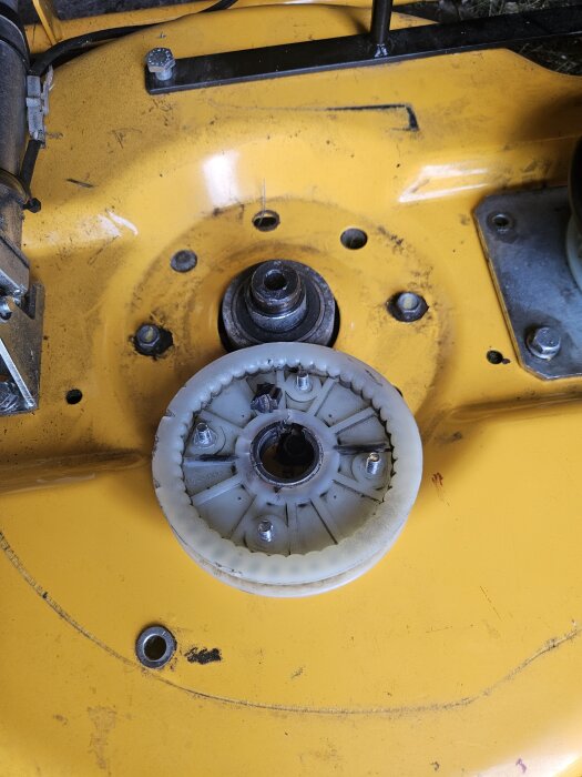 Gul maskindel med synligt kugghjul och metallfäste, del av maskin- eller motorutrustning.