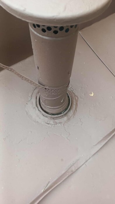 En närbild av en ventil på ett plåttak där tätning runt stosen behövs, synlig oläkage efter hårt regn.