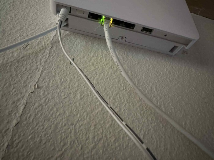 Mediaomvandlare från Icotera på väggen, med kablar anslutna och en grön ljusdiod som lyser.