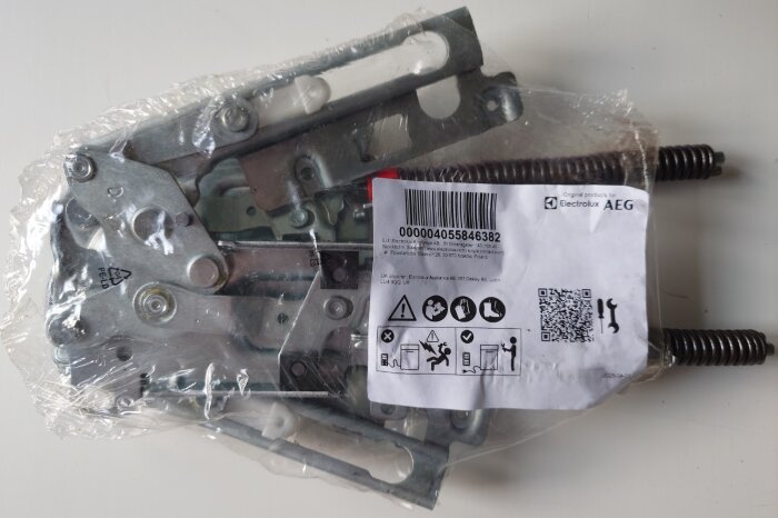 Förpackade gångjärn från Electrolux och AEG med etikett innehållande streckkod och QR-kod med monteringsanvisningslänk.