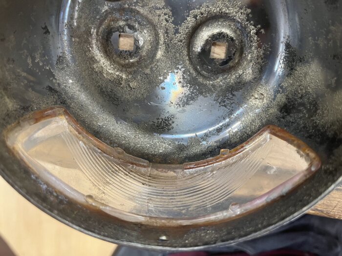 Gammal och rostig baklykta med sprucket glas, redo för renovering och återställning av funktionalitet enligt originaldesign.