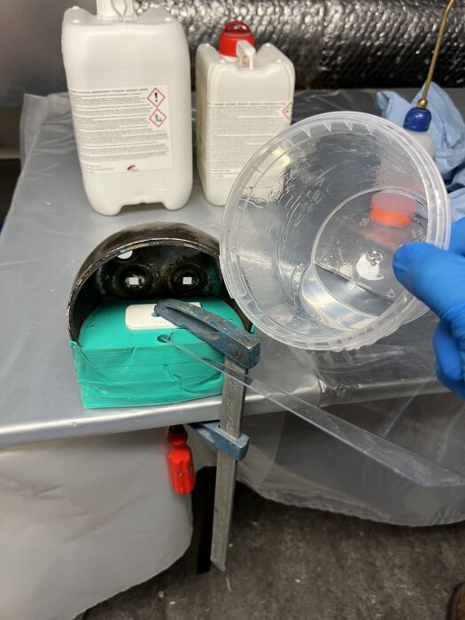 Gjutning av baklykta med silikonform, epoxi och verktyg i verkstadsmiljö, gamla behållare i bakgrunden, projekt pågår.