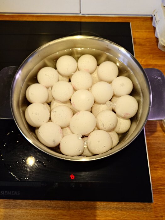 Kastryll med mÄnga Àgg som kokas pÄ en spishÀll, förbereds för frukost till mÄnga personer.