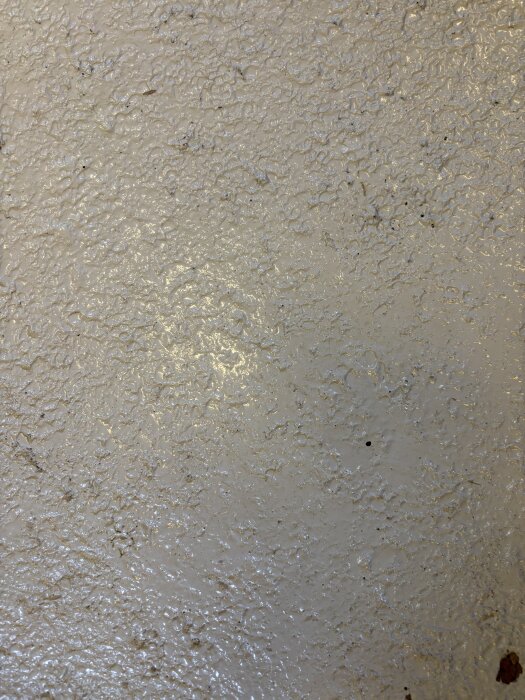 Epoxymålad asfaltsyta med ojämn struktur och glansig finish. Målningen gjordes med tvåkomponents epoxyfärg från Biltema.